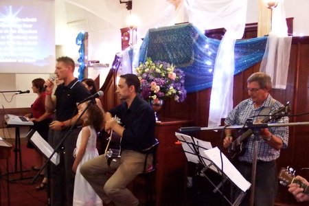 â€˜n Deel van die orkes en sangers tydens Stanford se gesamentlike Kerssangdiens, met ds Neil Ollewagen, self â€˜n knap sanger, met die mikrofoon in sy hand